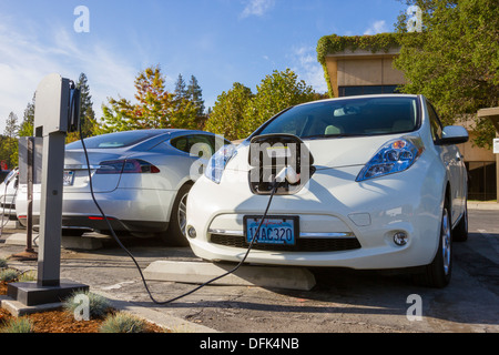 Nissan Leaf électrique plug-in voiture garée dans un stationnement EV au travail et branché sur une station de charge Banque D'Images