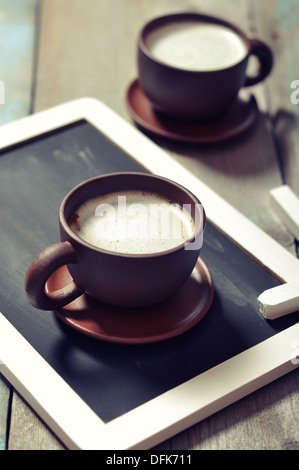 Deux tasses de café avec conseil d'ardoise sur fond de bois Banque D'Images