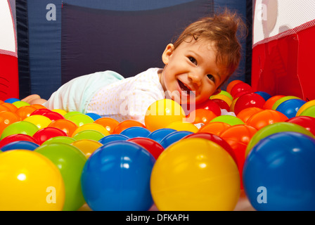 Happy Baby Boy lying on boules colorées dans un parc pour enfants Banque D'Images