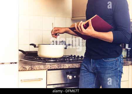 Homme avec pot en remuant cookbook Banque D'Images