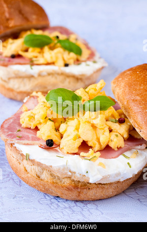 Oeufs brouillés, jambon et fromage blanc crème sur le bun Banque D'Images