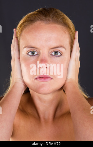 Une jeune femme couvrant ses oreilles avec ses mains les trois singes de la sagesse. Voir Pas de ne rien voir, ne rien dire Banque D'Images