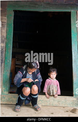 Groupe de la minorité Hmong noir femme broder schéma traditionnel en face de la porte de la chambre, Sa Pa, Vietnam Banque D'Images