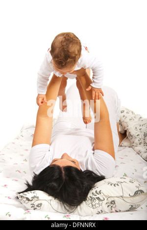 Mère jouant avec son bébé au lit dans leur maison Banque D'Images