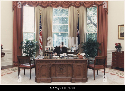 Cette photographie montre le président Ronald Reagan travaillant à son bureau dans le bureau ovale. Prise en 1985, elle reflète les fonctions présidentielles de Reagan et offre un aperçu de l'environnement de travail du président américain pendant son mandat. Banque D'Images