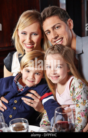 Famille heureuse avec deux enfants assis à la table de dîner Banque D'Images