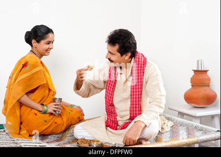 L'homme de manger de la nourriture avec sa femme assis près de lui Banque D'Images