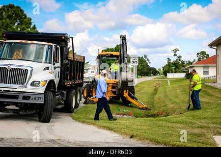 Travaux publics travailleurs Dept creuser et remplacement d'une évacuation d'eau de pluie bloqués dans un quartier résidentiel de Floride Banque D'Images