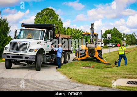 Travaux publics travailleurs Dept creuser et remplacement d'une évacuation d'eau de pluie bloqués dans un quartier résidentiel de Floride Banque D'Images