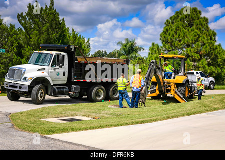 Travaux publics travailleurs Dept creuser et remplacement d'une évacuation d'eau de pluie bloqués dans un quartier résidentiel de Floride Banque D'Images