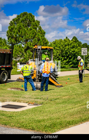 Travaux publics travailleurs Dept creuser et remplacement d'une évacuation d'eau de pluie bloqués dans un quartier résidentiel de Floride Banque D'Images