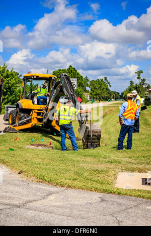 Travaux publics travailleurs Dept creuser et remplacement d'une évacuation d'eau de pluie bloqués dans un quartier résidentiel de Floride Banque D'Images