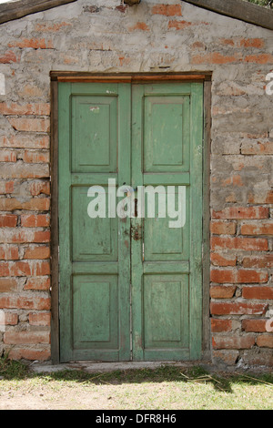 Une porte en bois vert dans un mur de briques d'adobe dans un bâtiment à Cotacachi (Équateur) Banque D'Images