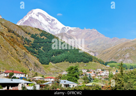 Vue sur le village, l'église de trinité Gergeti Stepantsminda et le Mont Kazbek dans les montagnes du Caucase en Géorgie Banque D'Images