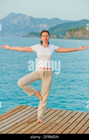 Girl en maintenant un équilibre en position debout sur une jambe sur la jetée Banque D'Images