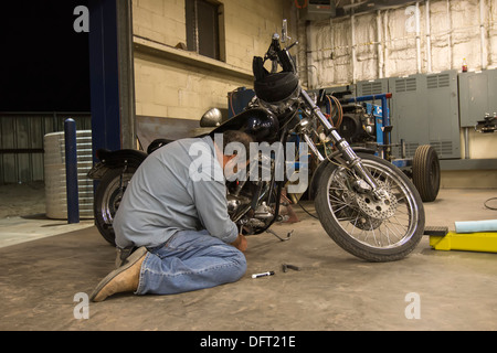 L'homme travaillant sur une moto de fabrication américaine dans un garage de mécanicien. Banque D'Images