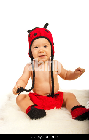 Happy Baby Boy in ladybug hat et bottes assis sur une couverture de fourrure Banque D'Images