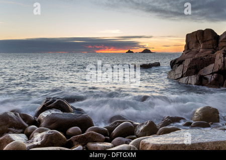 Se précipitant sur les vagues rochers arrondis au crépuscule à Porth Nanven Cove près de St Just à Cornwall Banque D'Images