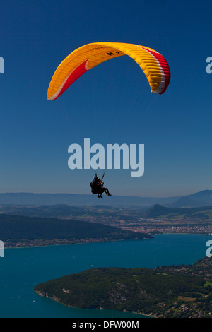 Deltaplane motorisé jaune contre un ciel bleu clair en survolant le Lac d'Annecy, Haute Savoie, France Banque D'Images