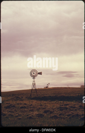 Un moulin à vent se dresse sur les terres du ranch vallonné près de Powder River, Wyoming. Le moulin à vent est utilisé pour le pompage de l'eau, une caractéristique commune dans l'agriculture rurale et les régions d'élevage. Banque D'Images