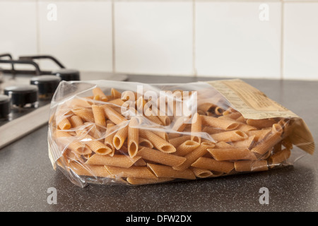 Paquets en plastique de blé entier pâtes penne sur une surface de travail de cuisine Banque D'Images