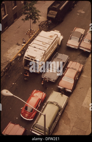 Un camion d'assainissement passe devant des voitures à double stationnement et des déchets de rue sur la 172e rue à Manhattan, illustrant les efforts de propreté urbaine. Banque D'Images