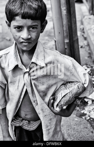 Basse caste indien garçon avec des paquets de riz dans une rue. L'Andhra Pradesh, Inde. Le noir et blanc Banque D'Images