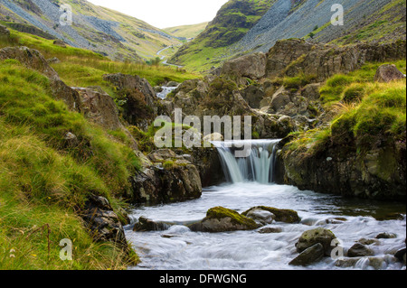 Une petite chute d'eau qui longe la route, près du bas de l'Honister Pass, Cumbria, Royaume-Uni. Banque D'Images