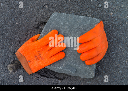 Une paire de gants du travailleur orange fluorescent jeter sur un pavé en pierre grise dans la rue à Peggy's Cove, en Nouvelle-Écosse. Banque D'Images