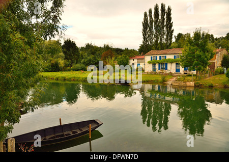 Punt amarré avec maison pittoresque et peupliers au bord opposé reflète dans la rivière. Près de Coulon, Deux-Sèvres, France Banque D'Images