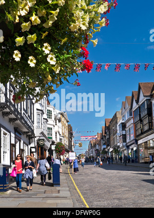 Guildford Shoppers historique High Street avec des fleurs d'été et Union Flags profitant du soleil Guildford Surrey Royaume-Uni Banque D'Images