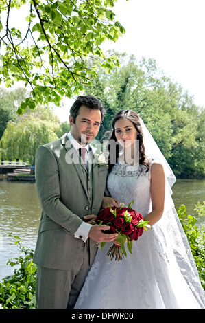 Belle Mariée et le marié récemment mariés dans église traditionnelle cérémonie, posant dans des motifs de riverside Banque D'Images