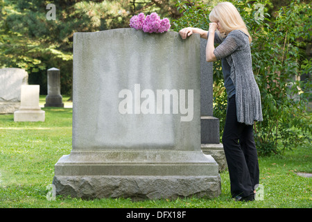 Femme pleure en repos sur pierre tombale du cimetière Banque D'Images