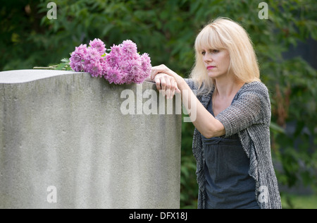 Femme pleure dans cemetery reposant sur pierre tombale en libre Banque D'Images