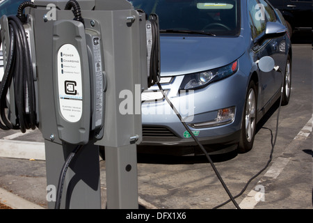 Des stations de recharge EV avec plug-in voiture électrique branché pour recharger sa batterie dans un milieu de terrain de stationnement Banque D'Images