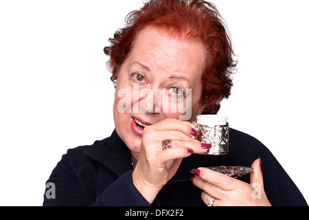 Femme Senior welcomingly tenant une tasse de café turc d'argent Banque D'Images