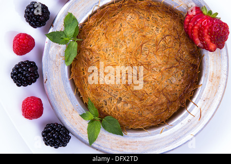 Kunefe dessert turc servi sur une plaque blanche avec la menthe et fraise en tranches le long de baies rouges et noires Banque D'Images