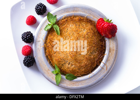 Kadayif dessert turc servi sur une plaque blanche avec la menthe et fraise en tranches le long de baies rouges et noires Banque D'Images