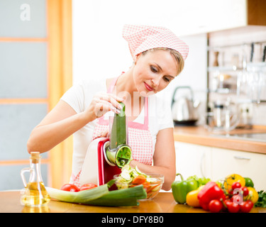 Femme couper des légumes avec l'appareil à la table de cuisine Banque D'Images