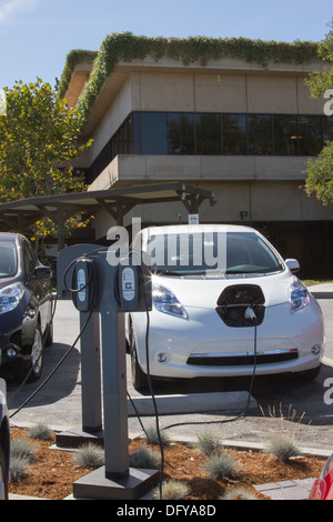 Plug-in voitures électriques branchée sur une station de recharge EV pour recharger leurs batteries dans un milieu de terrain de stationnement Banque D'Images