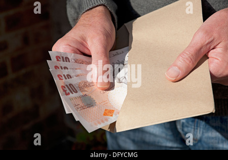 Gros plan de la main de l'homme tenant anglais dix livres billets cash billet de banque £10 argent payer des factures enveloppe brune Angleterre Royaume-Uni GB Grande-Bretagne Banque D'Images