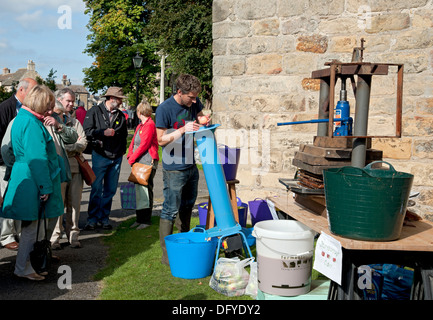 Les gens regardant homme personne pulpant des pommes extraction de jus de pomme Masham North Yorkshire Angleterre Royaume-Uni GB Grande-Bretagne Banque D'Images