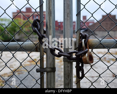 Chaîne rouillée et d'un cadenas sur le grillage à un lot vacant à Brooklyn, New York. Banque D'Images