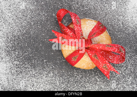 Noël sucré mince pie avec un ruban rouge attaché autour sur une ardoise conseil de refroidissement avec le sucre glace. Banque D'Images