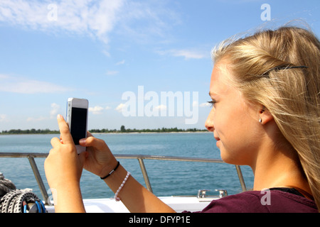 Smiling blonde avec un téléphone sur le bateau, horizontal Banque D'Images