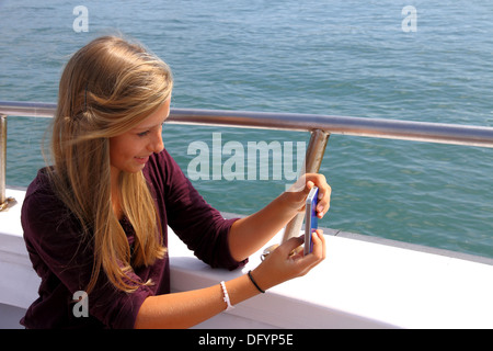 Heureux fille blonde avec un téléphone sur le bateau, horizontal Banque D'Images