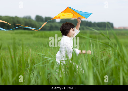 Excited boy sitting on the grass Banque D'Images