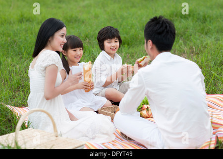 Heureux jeune famille faire un pique-nique sur l'herbe Banque D'Images