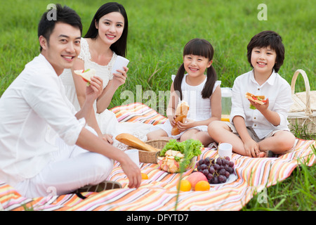 Heureux jeune famille faire un pique-nique sur l'herbe Banque D'Images