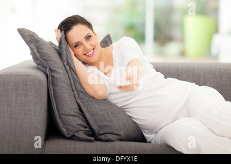 Portrait of cute femme enceinte à regarder la télévision à la maison Banque D'Images